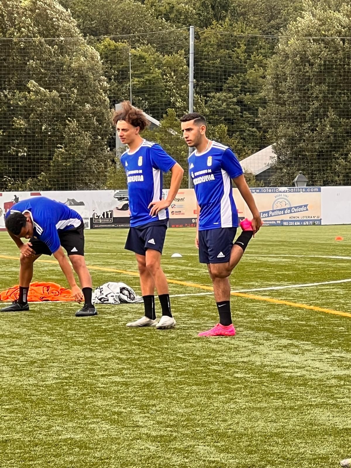 Soccer players in blue jerseys standing on a field during practice.