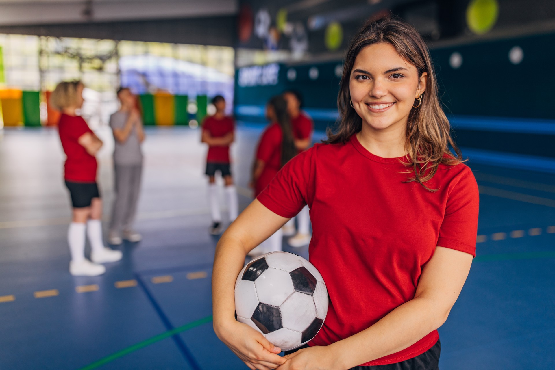 Female athlete indoor confident with soccer ball team ready